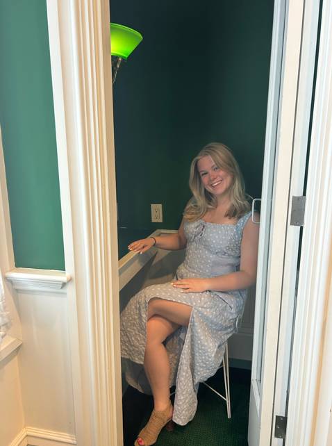 Olivia Darroch smiling while seated wearing a blue dress with white polka dots.
